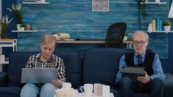 Senior couple in living room using modern gadget and technology to connect with internet. Modern old person browsing informations, surfing the web and connecting with the world video