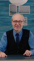 Vertical . POV of elderly aged man waving during a conference with business partners working from home. Senior person using internet online chat technology webcam making virtual meeting call connection video