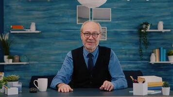 POV of elderly aged man waving during a conference with business partners working from home. Senior person using internet online chat technology webcam making virtual meeting call connection video