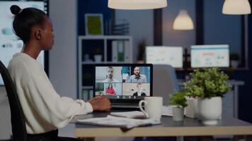 African businesswoman talking during conference with team in midnight using laptop in start up business office. Diverse workers talking during corporate meeting using technology network wireless video