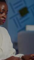 African bookkeeper working overtime calculating profit, taking notes, analysing financial documents sitting at desk in start-up financial company. Overworked woman doing overtime respecting deadline. video