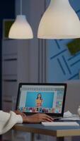 Dark skin freelancer retoucher woman working overtime on laptop with photo editing software. Professional graphic editor retouching photo of a client during night time in home office on performance pc video
