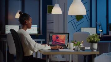 Dark skin gamer developer working at game in midnight from business office using professional laptop. African player testing online games on pc with modern technology network wireless. video