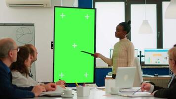 African businesswoman analysing annual financial reports standing in conference room pointing at green screen monitor. Leader explainig project strategy using greenscreen pc with chroma key display video