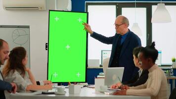 Mature businessman analysing annual financial reports standing in conference room pointing at green screen monitor. Leader explainig project strategy using mockup pc chroma key display in boardroom video