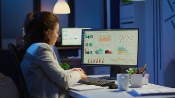 Busy woman working at night in front of computer taking notes writing on notebook annual reports, checking financial project. Focused employee using technology network wireless doing overtime for job video