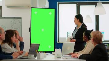 Leader of company presenting financial plan using mockup display in front of diverse team brainstorming. Manager explainig project strategy on green screen monitor with chroma key desktop in boardroom video
