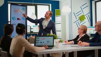 Business partner presenting company strategy to diverse team brainstorming in new startup office, analysing financial graphs from display, Multiethnical businesspeople working in professional start up video