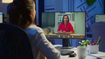 Manager woman talking with coworker during conference at midnight from business office planning financial strategy. Lady using modern technology network wireless discussing at virtual meeting video