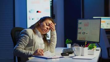 Tired freelancer comparing graphics from clipboard and computer working from business office overtime. Busy focused employee using modern technology network wireless reading typing, searching video