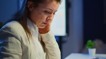 Close up of stressed busy woman with headache working from business office late at night. Tired focused employee using modern technology network wireless doing overtime for job checking reports video