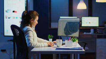 Tired designer engineer analizing new prototype of 3D model of the plant yawning working overtime. Industrial female worker studying turbine idea on pc showing cad software on device display video