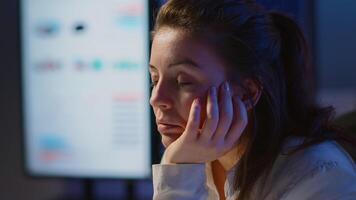 affärskvinna vem arbetade fram tills midnatt på projekt faller sovande i främre av bärbar dator i Start upp företag kontor, vilar på hand med stängd ögon. anställd använder sig av teknologi nätverk håller på med över tid video