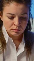 Vertical . Close up of overworked business woman looking exhausted at camera sighing working late at night in start-up business office. Focused employee using technology network wireless doing overtime for job video