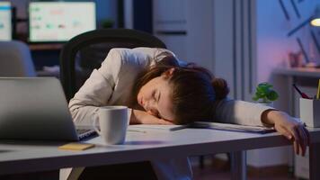Exhausted overload business woman falling asleep on desk with open laptop monitor while working in start up company office. Employee using modern technology network wireless doing overtime sleeping video