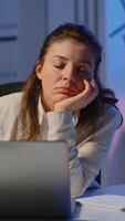 Vertical . Tired remote woman napping on chair waking up working on laptop in start up company office late at night. Busy employee using modern technology network wireless doing overtime closing eyes sleeping. video