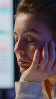 verticale . donna d'affari chi lavorato fino a mezzanotte su progetto caduta addormentato nel davanti di il computer portatile nel inizio su azienda ufficio, riposo su mano con chiuso occhi. dipendente utilizzando tecnologia Rete fare col tempo video