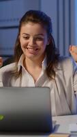 Vertical . Happy freelancer receving good news on laptop working overtime in start up company office. Enthusiastic employee using modern technology network wireless overworking studying writing, searching video
