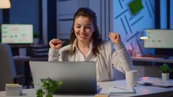 Happy freelancer receving good news on laptop working overtime in start up company office. Enthusiastic employee using modern technology network wireless overworking studying writing, searching video