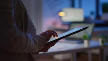 Close-up photo of woman hands typing on tablet checking financial graphs standing in start-up office late at night. Businesswoman using social network, texting and blogging working overtime for job video