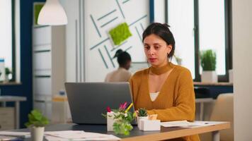 Satisfied manager checking financial statistics and graphs typing on laptop sitting at desk working in financial startup company. Diverse team analyzes statistics data in modern office video