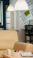 Interior of cozy light company room with small table and confortable couch, modern stylish chairs and desktop computer, all ready for employees. Empty spacious office of creative working space. video