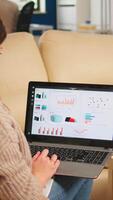 Close up of back view young entrepreneur sitting on couch in office using laptop computer while colleagues working on background. Multiethnic coworkers planning new financial project in modern company video