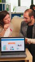 Diverse colleagues employees cooperating in office discussing at workplace, analysing graphs sitting on couch. Business coworkers planning start up business project, brainstorming in corporate office video