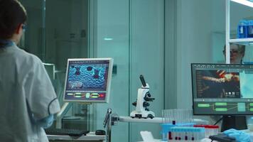 Chemist nurse working on computer in scientific modern equipped laboratory at night. Stuff examining vaccine evolution using high tech and technology researching treatment against covid19 virus video