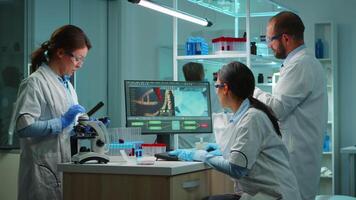 Team of doctors studying DNA mutation, chemist checking tests from tubes while nurses taking notes on notebook and pc. Scientists examining virus evolution using high tech for vaccine development. video