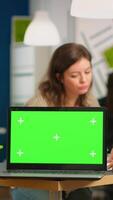 Group of business people discussing company plan with mockup laptop in front of camera, pc ready for financial project presentation placed on desk. Leader using green screen pc with chroma key display video