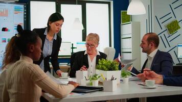 Woman secretary bringing documents and coffee to executive director while multiethnic team planning financial strategy during business conference. Manager briefing teamworkers during brainstorming. video