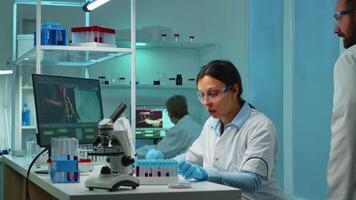Research chemists working at night in laboratory with high tech analyzing blood and genetic material samples with special program in modern equipped lab. Team examining virus evolution video