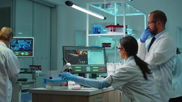 Research scientists working on pc with medical equipment analyzing blood and genetic material samples with special program in modern equipped laboratory. Multiethnic team examining virus evolution video