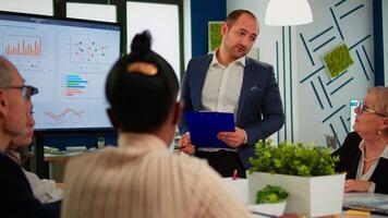 Business leader presenting company strategy to diverse team using digital interactive whiteboard brainstorming analysing financial graphs, Multiethnical businesspeople working in professional start up video