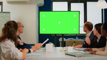 Tv green screen mockup ready for presentation placed in front of desk while business people working in broadroom. Employees using digital chroma key interactive whiteboard with mock up display monitor video