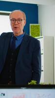 Experienced project leader analysing financial presentation during business conference in brainstorming room using digital devices. Multiethnical team working in professional startup company during meeting video