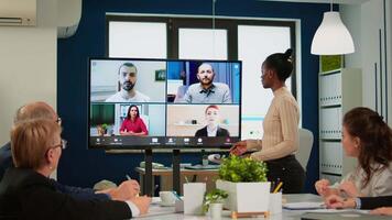 Preto Gerente mulher falando com remotamente colegas em ligar às televisão tela, apresentando Novo o negócio parceiros. confiante empresária falando para rede cam transmissão webcast treinamento, fazendo conectados conferência ligar video