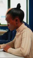 African businesswoman reading documents, signing its while business partners sharing paperwork sitting at conference table in broadroom. Executive director meeting shareholders in start up office video