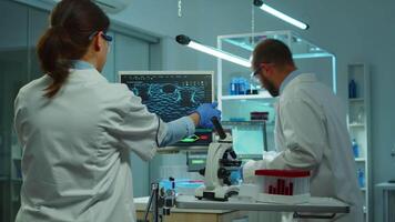 equipe do médico pesquisa cientistas conduzindo vacina desenvolvimento com Socorro do Alto tecnologia, teste tubos, micropipeta e escrevendo baixa análise resultados em computador dentro moderno equipado laboratório às noite video
