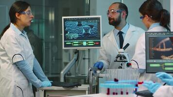 Team of medical researchers conducting vaccine development with help of high tech, test tubes, micropipette analysing results and planning next steps working at night in modern equipped laboratory video