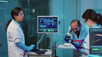 enfermeira segurando tábua computador com científico informações enquanto químico usando microscópio com químico teste tubo aproximar, dentro laboratório fundo às noite. médico Ciência pesquisa e desenvolvimento conceito video