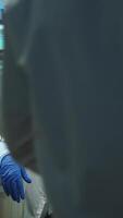 Vertical . Portrait of scientist nurse looking tired at camera sitting in modern equipped laboratory late at night. Team of specialists examining virus evolution using high tech for research, vaccine development video