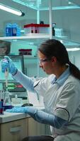 Vertical . Scientist woman pipetting liquid to test tube working in equipped lab late at night. Chemists examining virus evolution using high tech for scientific analysis of treatment development against covid19 video