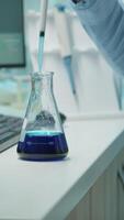 Vertical . Close up of scientis testing liquid sample late at night using micropipette for medical treatment in laboratory. Team examining virus evolution using high tech for vaccine development against covid19 video