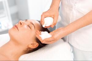 Esthetician preparing to apply cleansing foam on face of woman photo