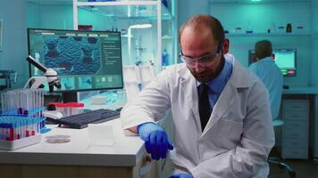 Exhausted portrait of chemist doctor looking up at camera sitting in equipped lab working late at night. Examining virus evolution using high tech and chemistry tools for vaccine development. video