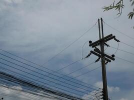 Electrical poles and cables for use in homes There is a sky and trees in the background photo