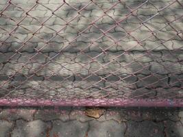 mesh wire fence has a cement floor and tree shadows in the background photo