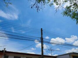 Electrical poles and cables for use in homes There is a sky and trees in the background photo